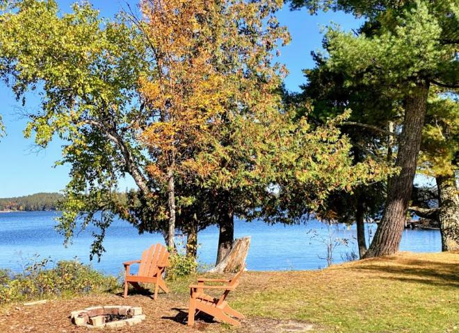 Private yard with shoreline, picnic table, and firepit.