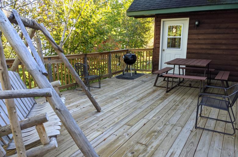 Deck area with swinging bench, picnic table, and charcoal grill.